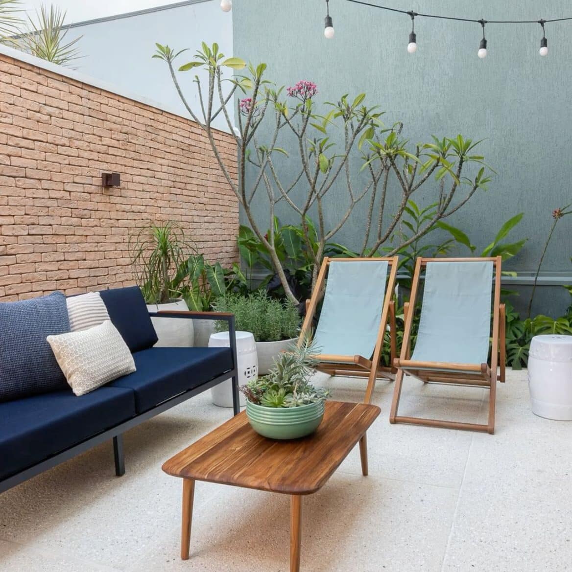Terraza con sillón azul de dos cuerpos, piso blanco y dos reposeras color celeste pastel.